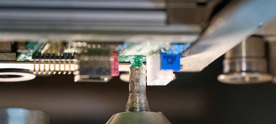 Detailaufnahme einer Leiterplatte in einer Prüf- und Messvorrichtung bei GLÜCK Industrie-Elektronik.
